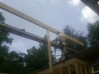 Carpenter setting a ridge beam over a new addition frame — Ice Dam Removal by Roofing Brothers in Craigville