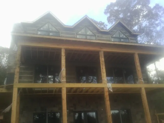 Dormers and porch framing on a large log home under construction — Roof Coating work by our crew in Craigville