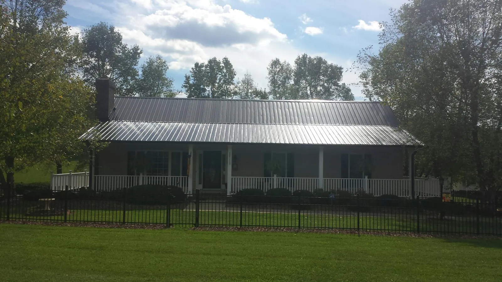Gray metal roof on a brick ranch with a full width front porch — Gutter Guard Installation work by our crew in Craigville