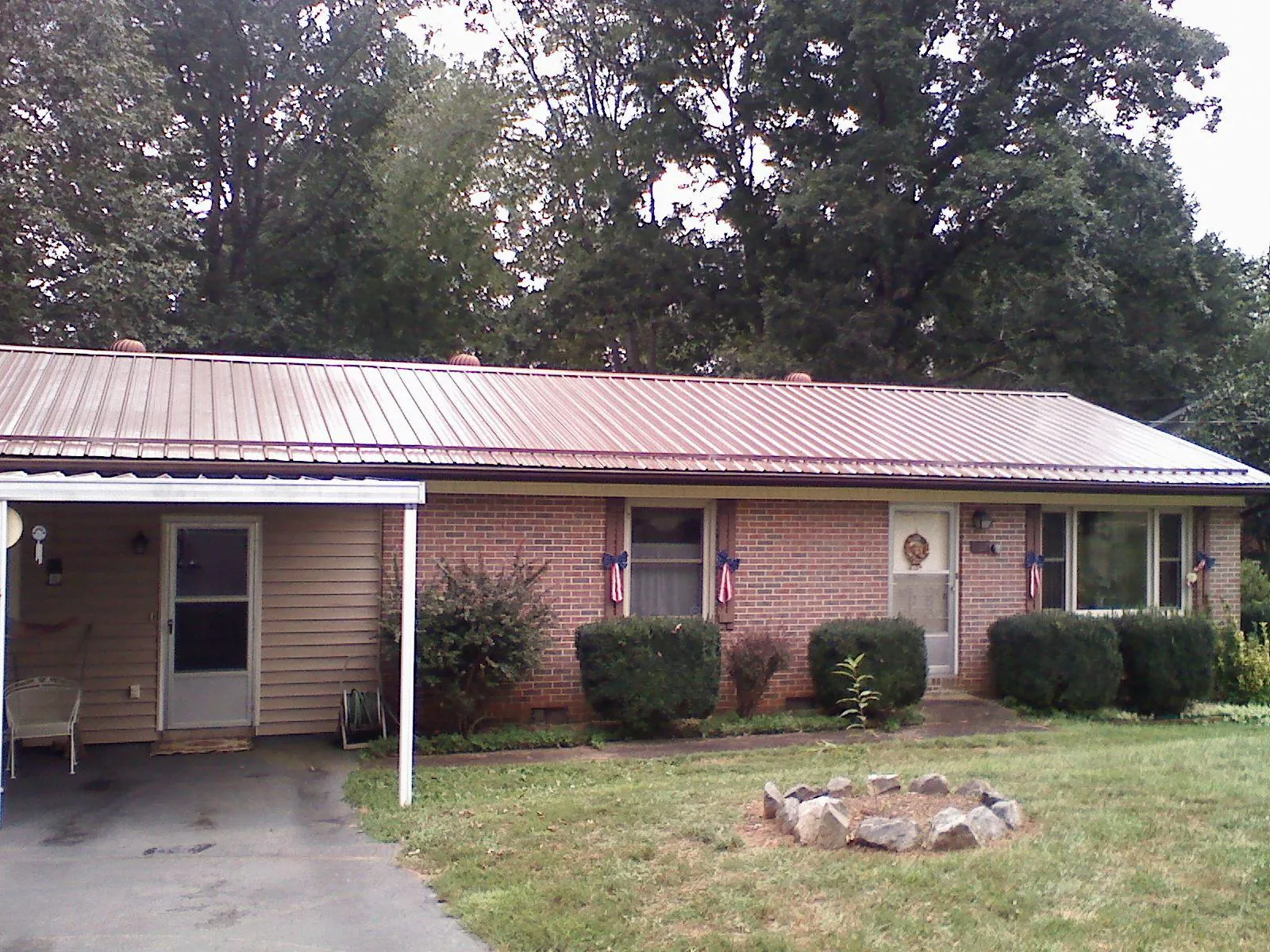 Bronze metal roof and carport on a brick ranch home — Roof Repair work by our crew in Craigville