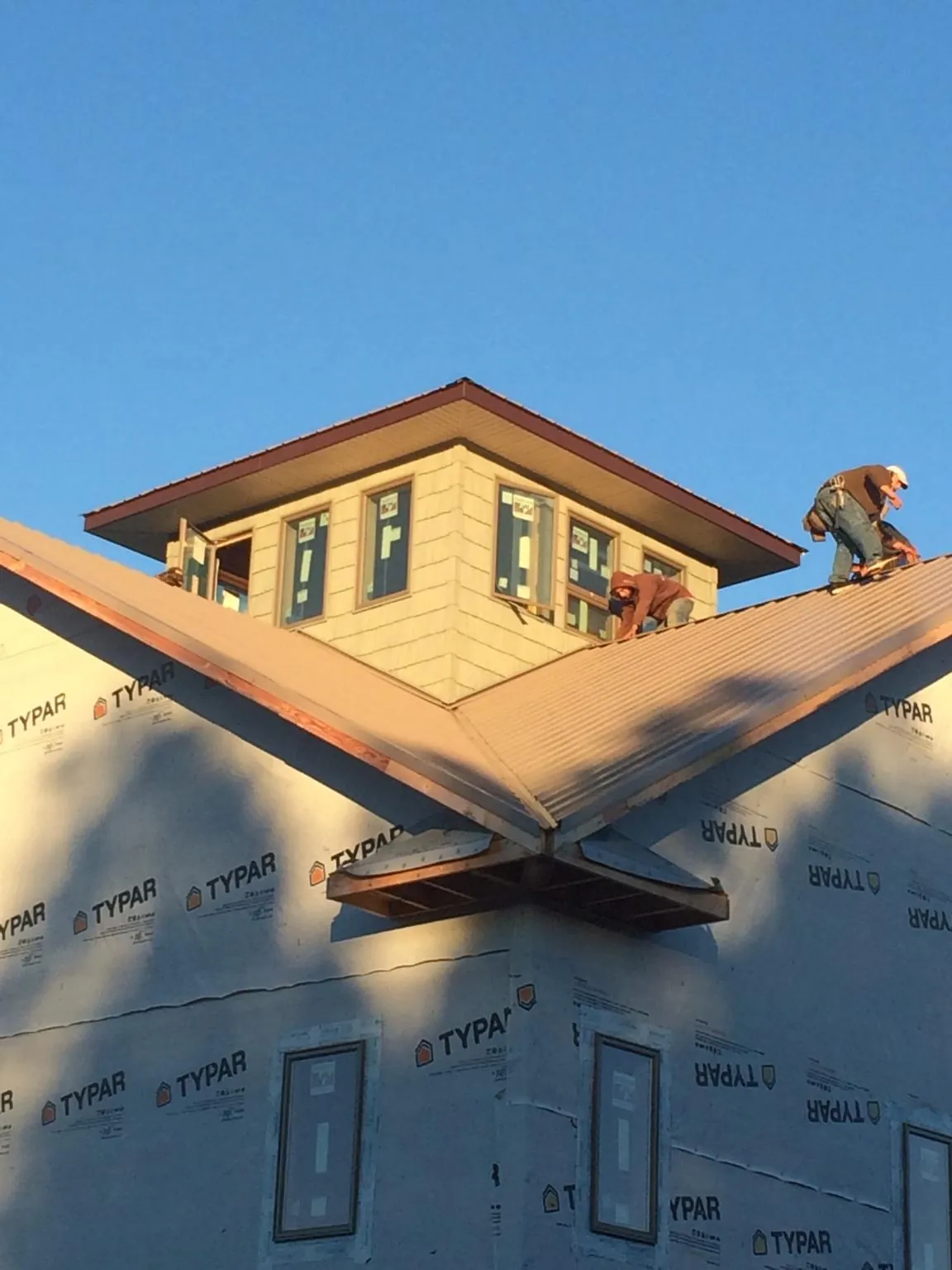Roofers working around a rooftop cupola on a new metal roof at sunset — Roof Waterproofing in Craigville by Roofing Brothers